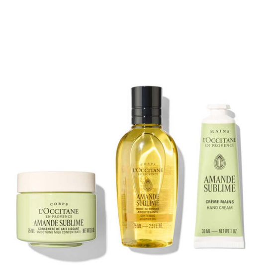 Three L'Occitane en Provence Amande Sublime hand care products arranged on a white background: a pale green body cream jar, a yellow oil bottle with a black cap, and a pale green hand cream tube.