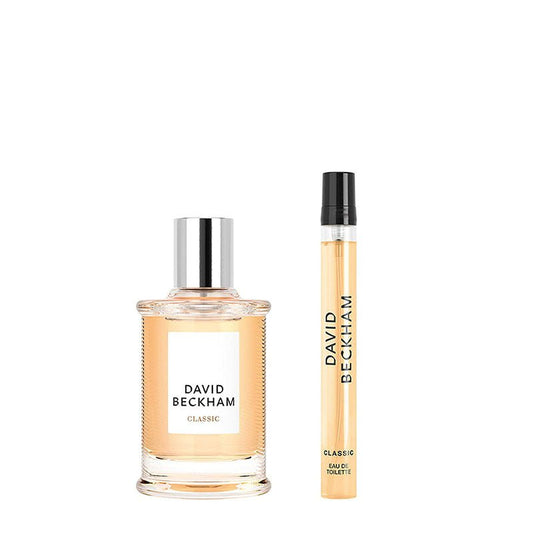 David Beckham Classic Eau de Toilette set featuring a clear glass bottle with a silver cap and a matching travel spray vial, both filled with a light peach-colored fragrance liquid, on a solid white background.