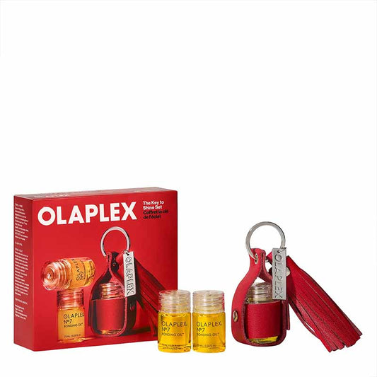 Olaplex Key to the World fragrance set with a red retail box, two small amber bottles with yellow liquid, and a red leather keychain with silver keyring and tassel on a white background.