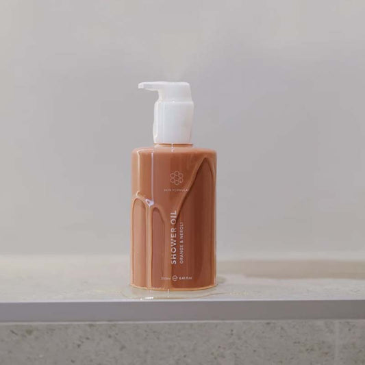 Skin Formulas Shower Oil with product dripping down the sides of the bottom, a clear gel like texture, the product is sitting on a bathroom counter