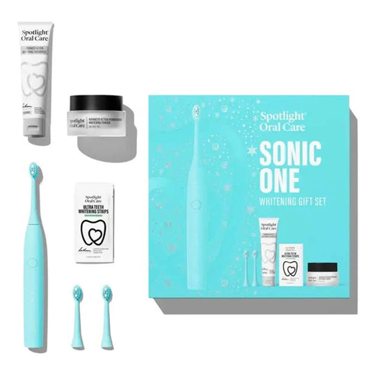 Spotlight Oral Care Sonic One Whitening Gift Set arranged on a white background, including a turquoise electric toothbrush, two extra brush heads, a toothpaste tube, a whitening cream jar, whitening strips, and the branded gift box.