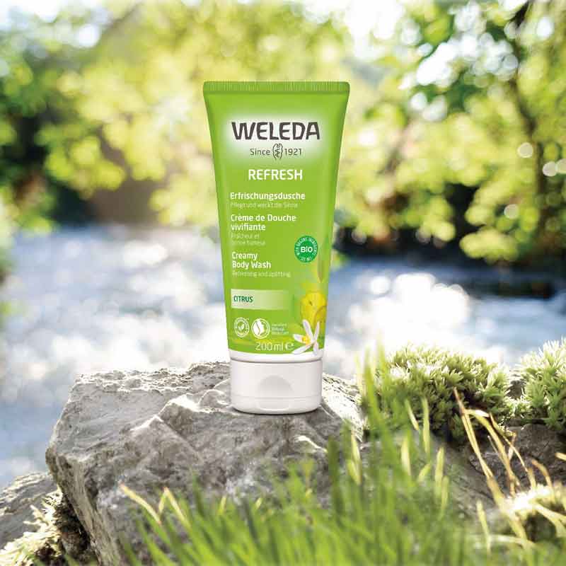 Weleda Citrus Refresh Creamy Body Wash Sitting On Edge Of Lake In Forest