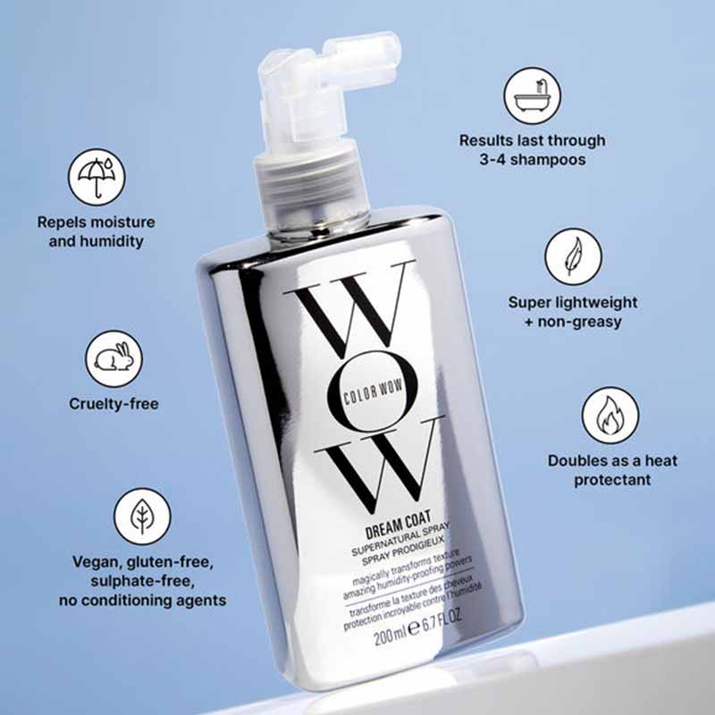 A bottle of Color Wow Dream Coat Super Natural Spray shown on a light blue background with feature callouts around it. The bottle is metallic silver with a clear pump and large black 'W' lettering.