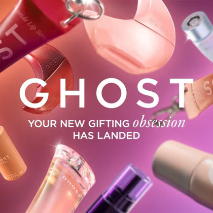 A promotional graphic for GHOST cosmetics showing multiple floating cosmetic products on a pink and purple gradient background with large white text reading 'GHOST YOUR NEW GIFTING obsession HAS LANDED'. Visible products include lip gloss, a compact powder, a tube, and a bottle, all branded GHOST.