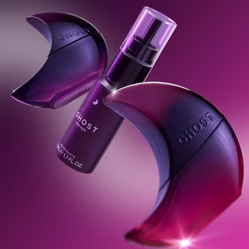 A purple and black perfume bottle labeled GHOST by Chloé, shown with two matching crescent-shaped decorative pieces on a pink-purple gradient background.