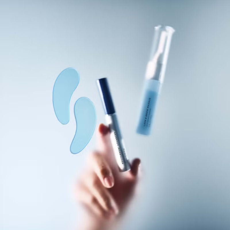 Revitalash Brow Refresh Collection frosted image of products through frosted glass and a hand grabbing the middle product