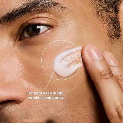 Close-up of a person applying or spreading a white cream on their cheek, with a circled area highlighting the product and text that says it targets deep static wrinkles and pores.