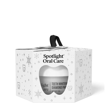 Spotlight Oral Care Teeth Whitener Diamond Pap in a white gift box with a black handle, decorated with subtle gray snowflakes and tooth icons.