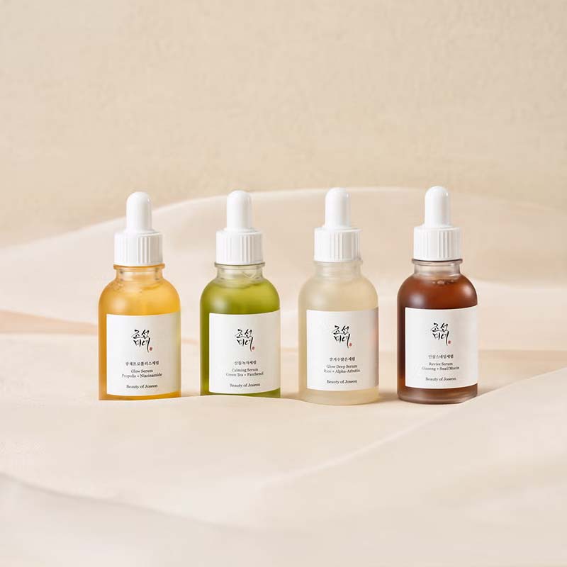 Collection of serums on a bed of linen sheets