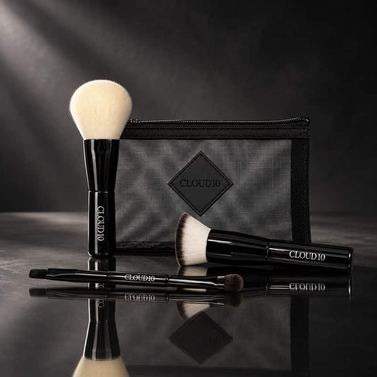 Cloud 10 On the Go Travel Brush Set with black makeup brushes and mesh makeup bag on a dark reflective surface