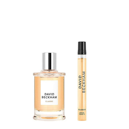 David Beckham Classic Eau de Toilette set featuring a clear glass bottle with a silver cap and a matching travel spray vial, both filled with a light peach-colored fragrance liquid, on a solid white background.