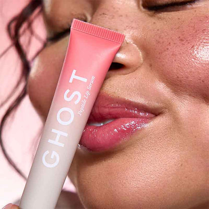 Person applying pink lip balm labeled 'Ghost' to their lips.
