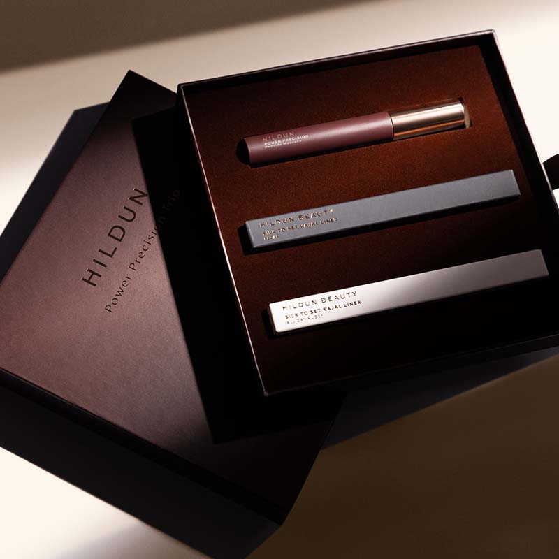 Hildun Beauty Power of Youth makeup set in a dark brown box, featuring a mauve lip product and two silver cosmetic tubes, with the branded box lid placed beside it.