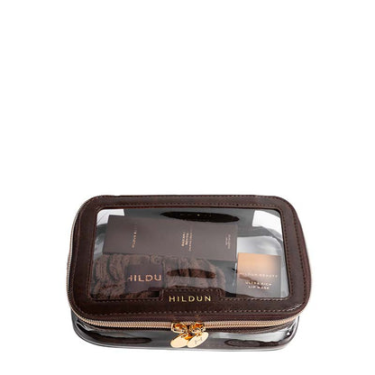 A Hildun cosmetic pouch in dark brown faux leather with a clear window showing makeup items inside, featuring a gold-tone zipper and logo on a white background.