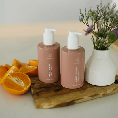 Skin Formulas Hand Wash and Hand Lotion Image, on a wooden platter with lavender in a vase and sliced oranges beside each product