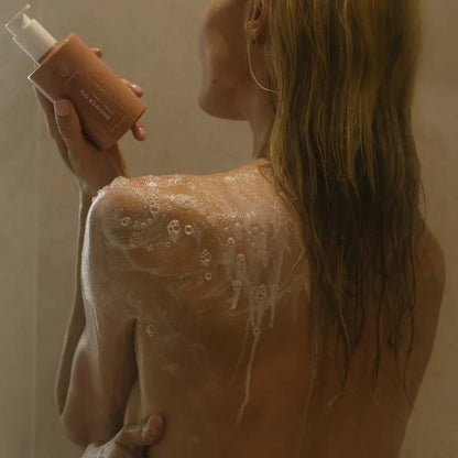 Skin Formulas Shower Oil Image of the product in a ladies hand, she is in the shower with suds on her shoulder