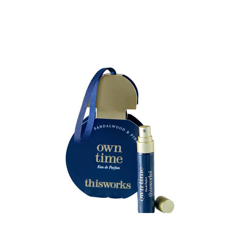 A Sandalwood & Pine Eau de Parfum gift set by thisworks, featuring a large blue pear-shaped box with a gold interior and handle, alongside a matching blue and gold spray bottle and its cap, on a white background.