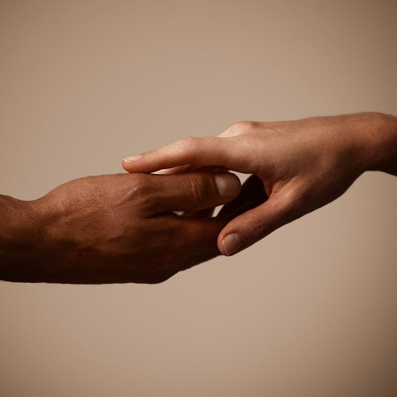 Two human hands reaching toward each other against a plain warm beige background.